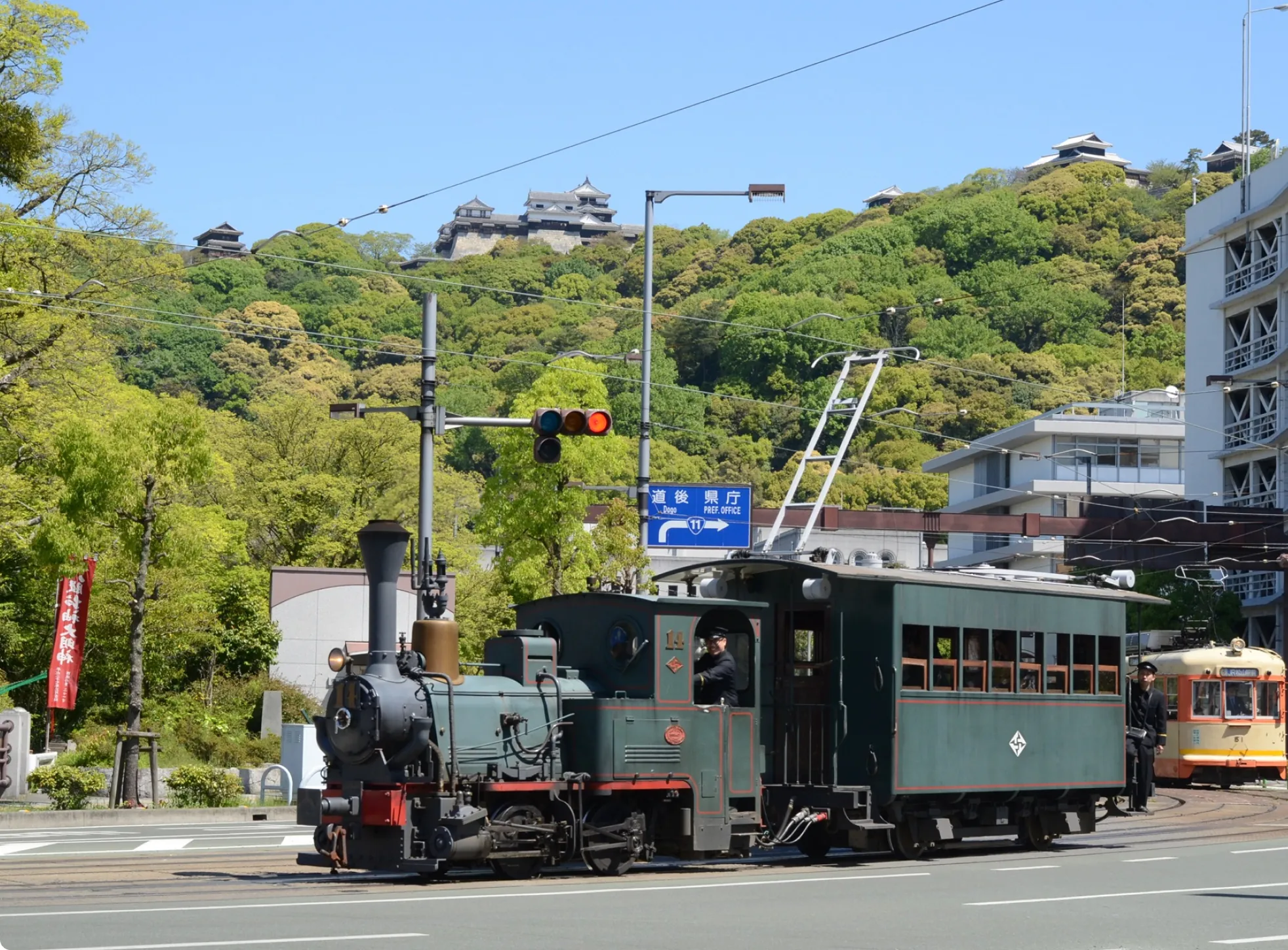 松山城のある山を背景に、路面を走る坊っちゃん列車（路面電車）。